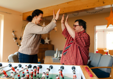 Eine Frau und ein junger Mann klatschen hinter einem Kickertisch ab