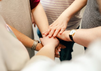 Viele Menschen halten die Hände zusammen.