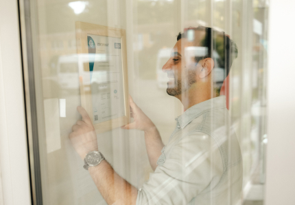 Ein Mann hängt ein Zertifikat an die Wand.